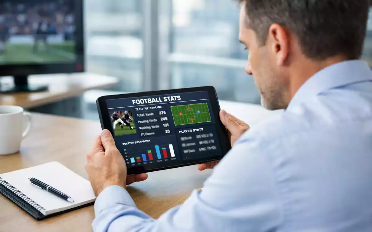 Analista deportivo revisando estadísticas de fútbol en una tablet con gráficos de rendimiento