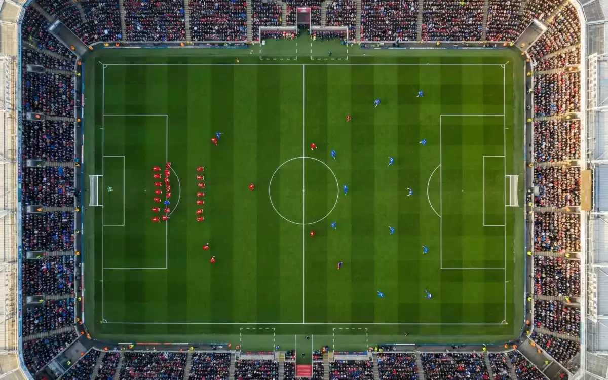 Vista aérea de un partido de fútbol mostrando la distribución táctica de los jugadores en el campo