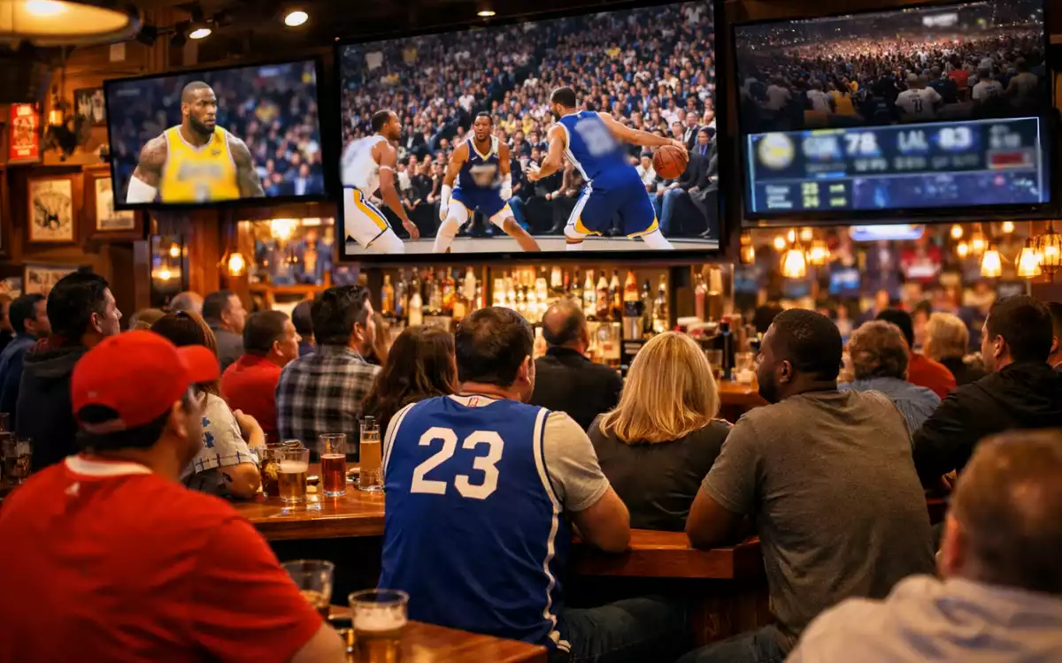 Aficionados viendo un partido de baloncesto NBA en un sports bar americano con pantallas mostrando estadísticas