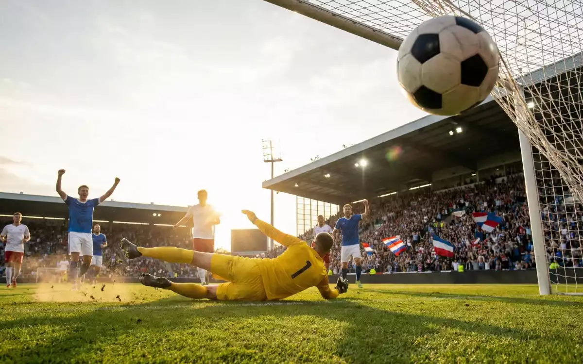 Celebración de gol en un partido de fútbol con el portero derrotado y la red moviéndose